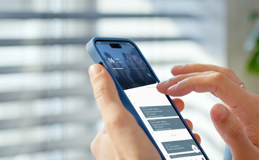 Une personne tient un smartphone affichant une application de messagerie avec plusieurs conversations.